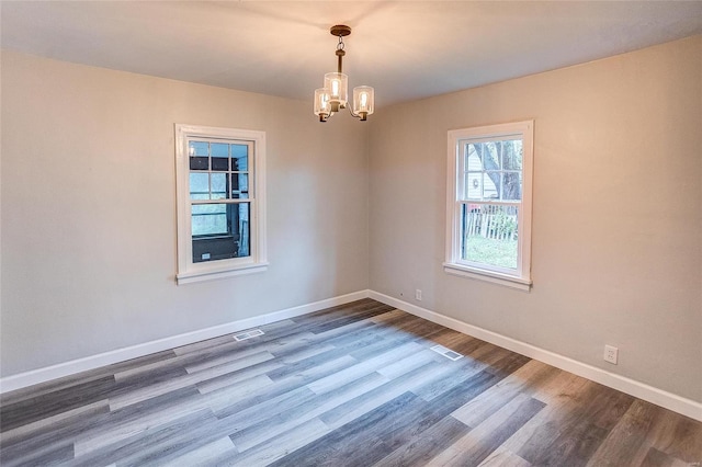 unfurnished room with a chandelier, wood finished floors, and baseboards