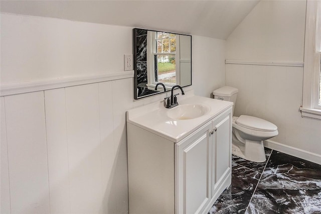 half bath with marble finish flooring, toilet, vanity, vaulted ceiling, and a wainscoted wall