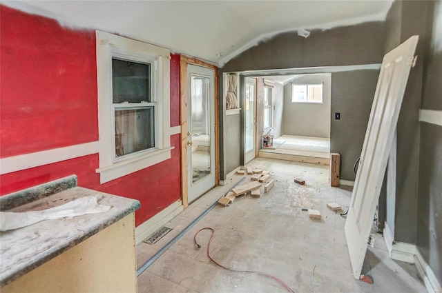 miscellaneous room featuring lofted ceiling and baseboards