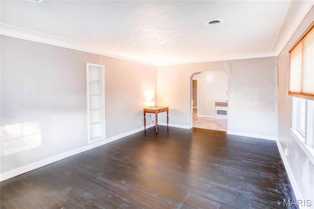 219 Highland St, Carrollton, IL 62016 - empty room with arched walkways, wood finished floors, ornamental molding, built in shelves, and baseboards