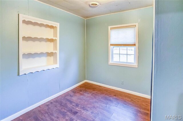 219 Highland St, Carrollton, IL 62016 - empty room featuring wood finished floors, built in shelves, baseboards, and ornamental molding