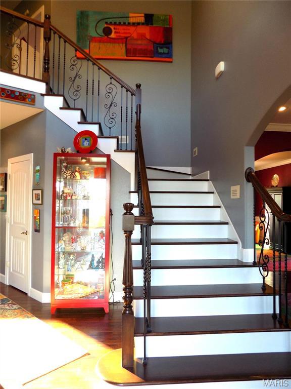 13185 Jenna Ln, Rolla, MO 65401 - stairway featuring arched walkways, wood finished floors, baseboards, and a high ceiling