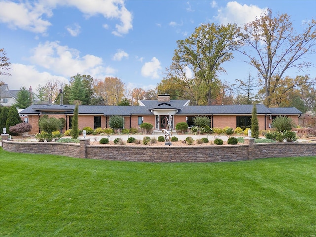 view of front of house featuring a front yard, brick siding, and a chimney