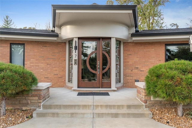 view of exterior entry featuring brick siding and french doors