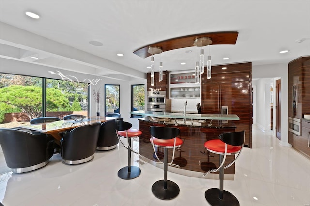 kitchen with recessed lighting, healthy amount of natural light, stainless steel double oven, decorative light fixtures, and a kitchen breakfast bar