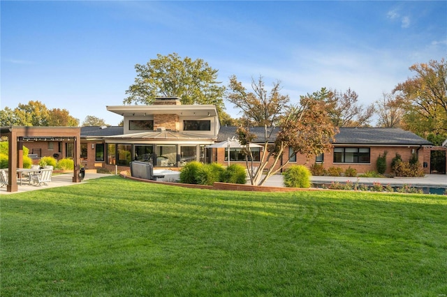 back of property featuring a yard, a patio, a chimney, and brick siding