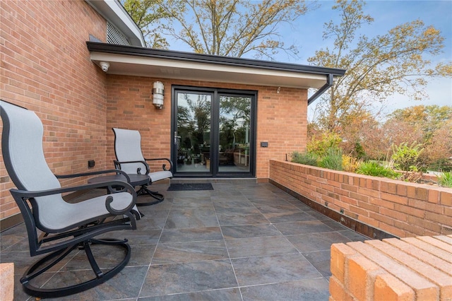 property entrance with brick siding, a patio, and a security system