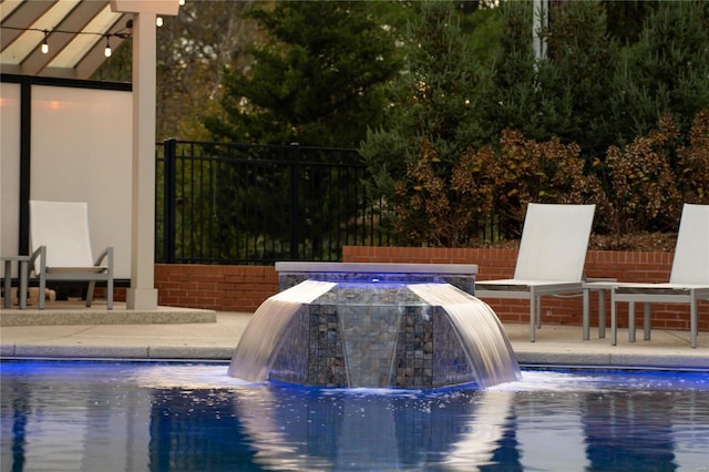 view of swimming pool featuring fence, a fire pit, and a patio area