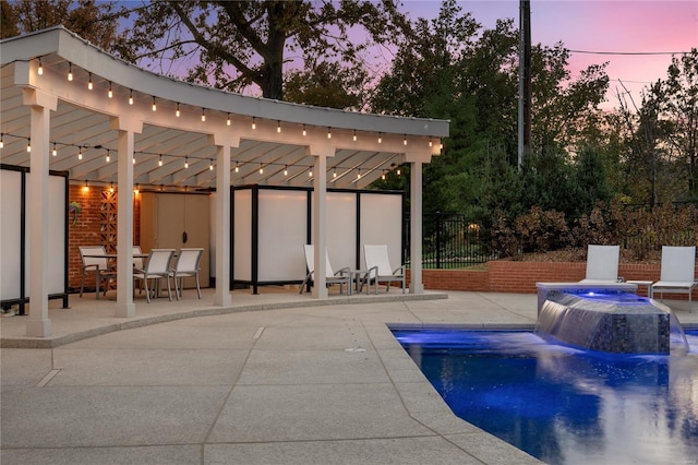 pool at dusk featuring a patio and fence