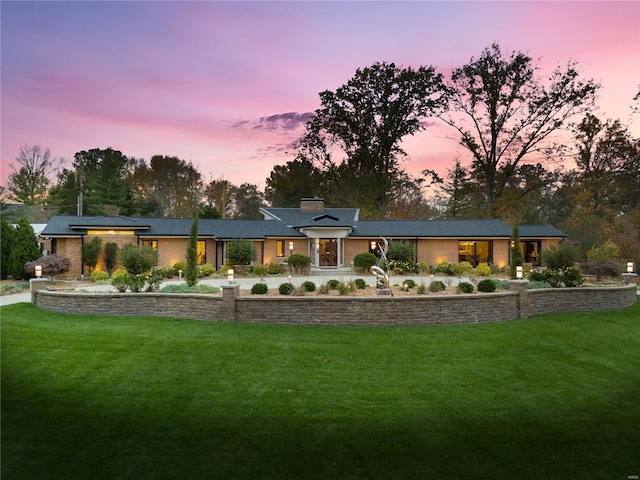 view of front of property with a front yard, a chimney, and brick siding