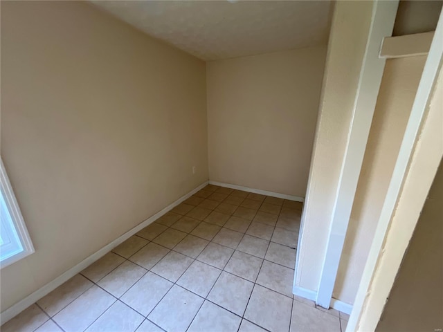 unfurnished room with light tile patterned floors and baseboards
