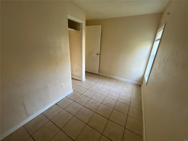 empty room with light tile patterned floors and baseboards