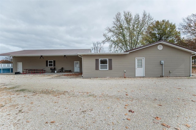 back of house with metal roof and a patio