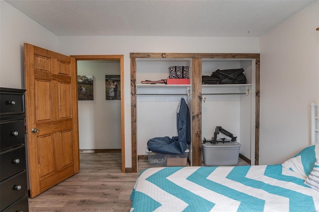 bedroom featuring light wood-style flooring, a closet, and a textured ceiling