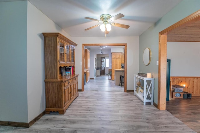 corridor featuring light wood finished floors and baseboards