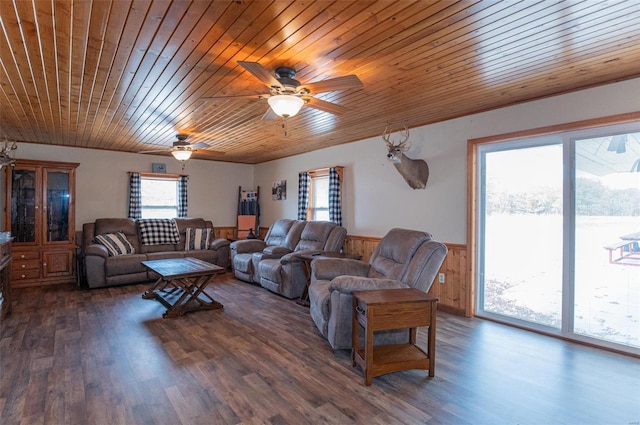 living area featuring a wainscoted wall, wood ceiling, dark wood-style flooring, and a ceiling fan