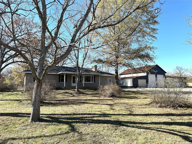 ranch-style house featuring a front yard, an outbuilding, and a detached garage
