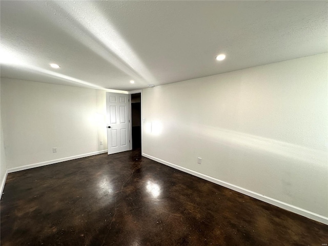 unfurnished room with finished concrete floors, baseboards, and recessed lighting