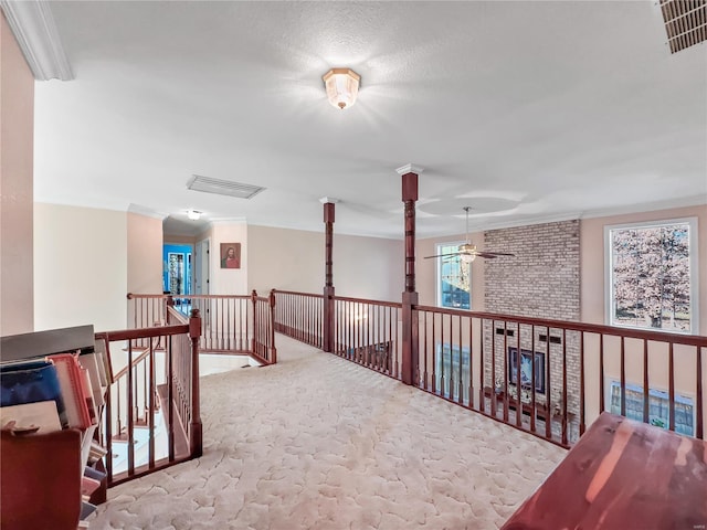 hallway with carpet floors, ornamental molding, an upstairs landing, and ornate columns