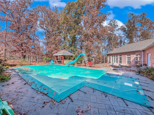 view of pool with a water slide, a gazebo, a patio area, and a covered pool
