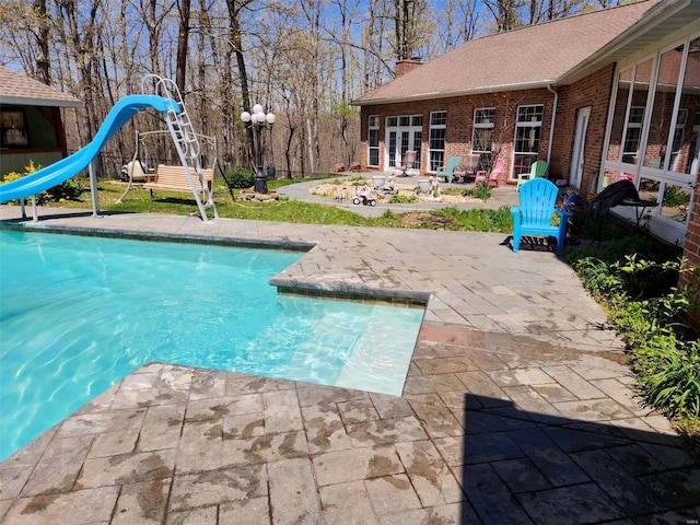 swimming pool featuring a water slide and a patio area