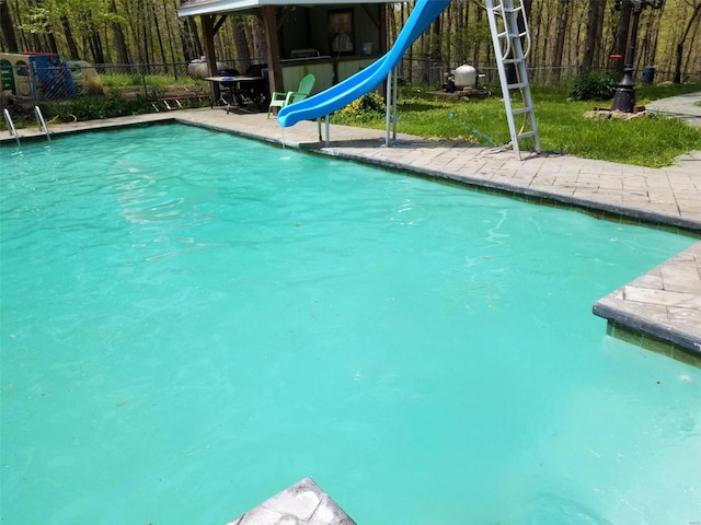 view of swimming pool featuring a water slide and fence