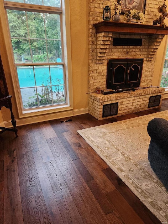 living area featuring a fireplace, dark wood-style flooring, and baseboards