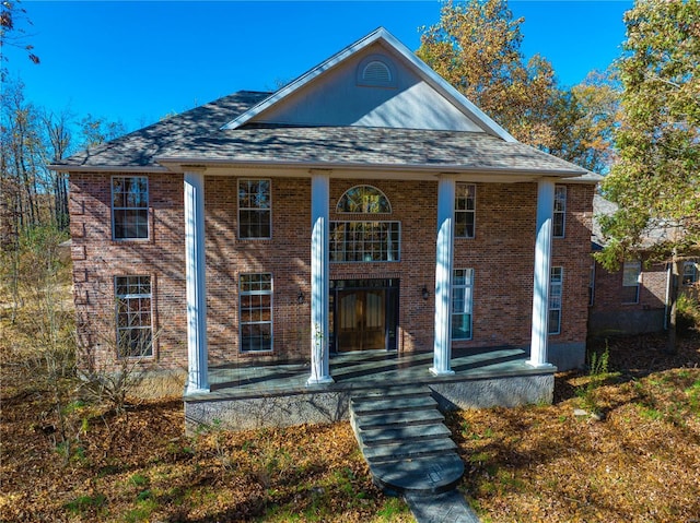 greek revival inspired property with french doors, brick siding, and a shingled roof