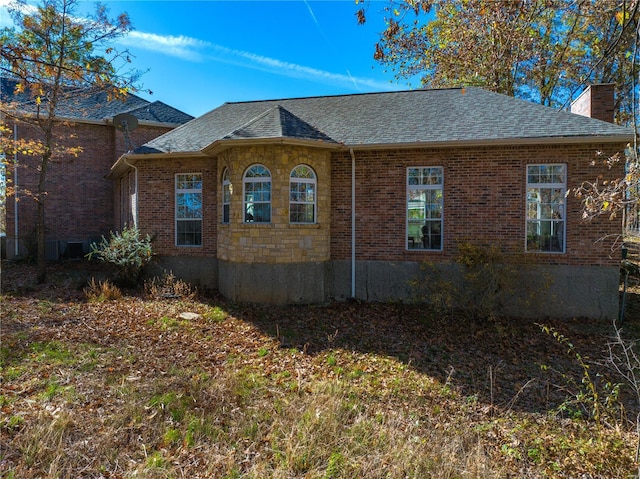view of side of home featuring a chimney, roof with shingles, and brick siding