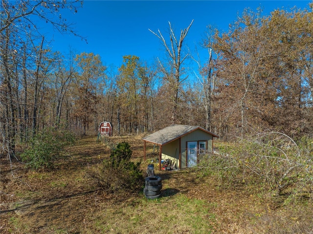 view of property exterior with an outdoor structure and a wooded view