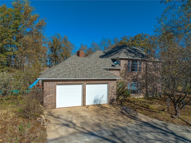 view of front of home with concrete driveway, a chimney, brick siding, a garage, and roof with shingles