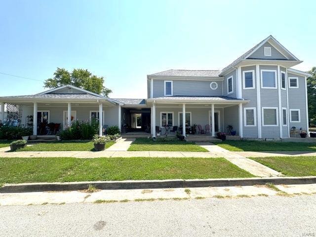 view of front of home with a porch and a front lawn