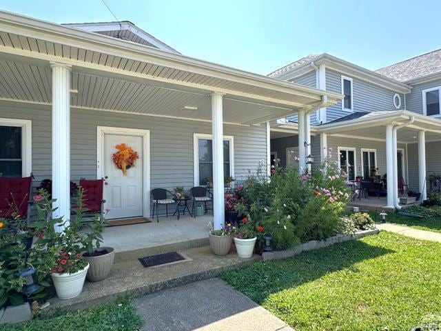 view of exterior entry with a porch and a yard