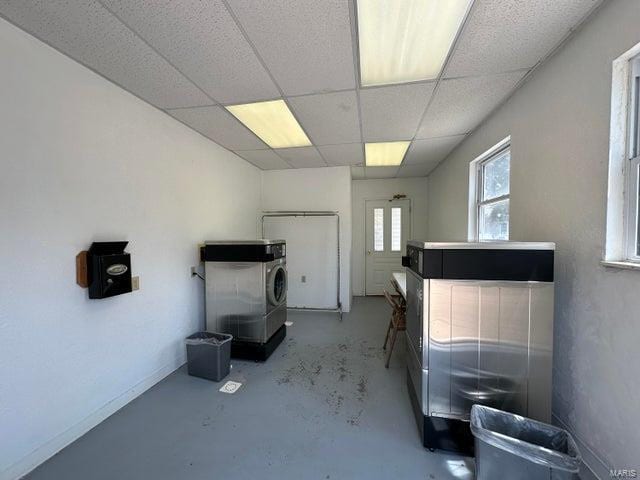 miscellaneous room with finished concrete floors, a drop ceiling, and baseboards