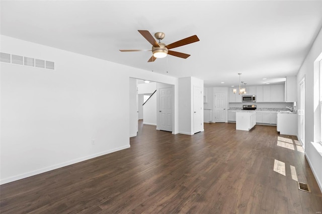 3139 White Pine Dr, Imperial, MO 63052 - unfurnished living room with a chandelier, a ceiling fan, dark wood-style flooring, and baseboards