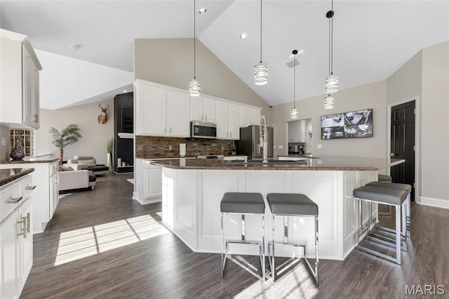 809 Peruque View Ct, Wentzville, MO 63385 - kitchen featuring appliances with stainless steel finishes, dark wood-style floors, a kitchen island, backsplash, and a breakfast bar