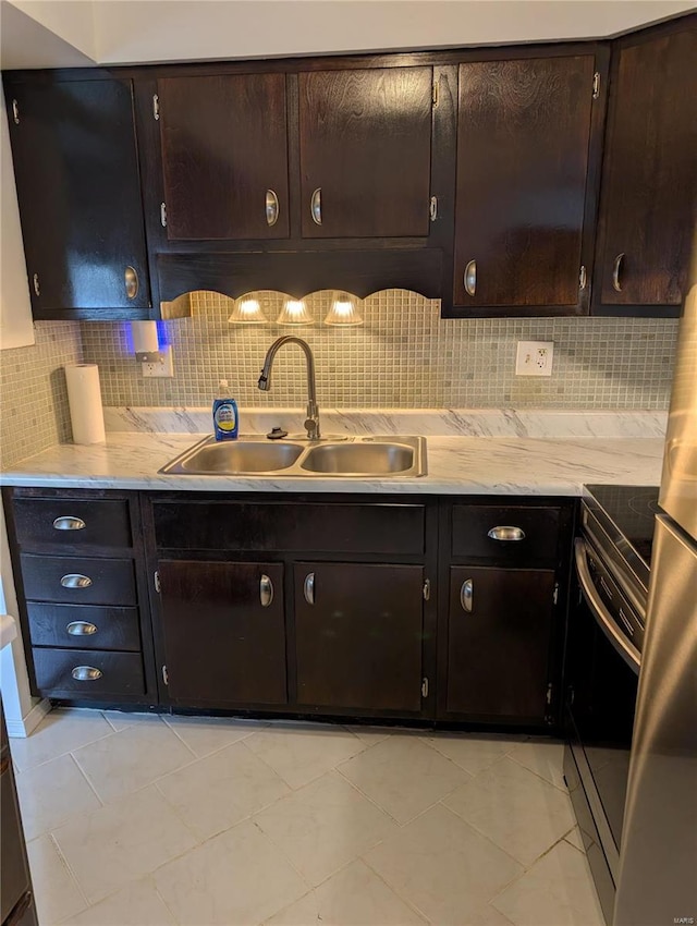 kitchen featuring a sink, stainless steel range with electric cooktop, backsplash, and light countertops