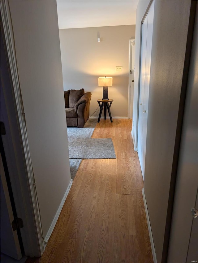 corridor with light wood-style flooring and baseboards