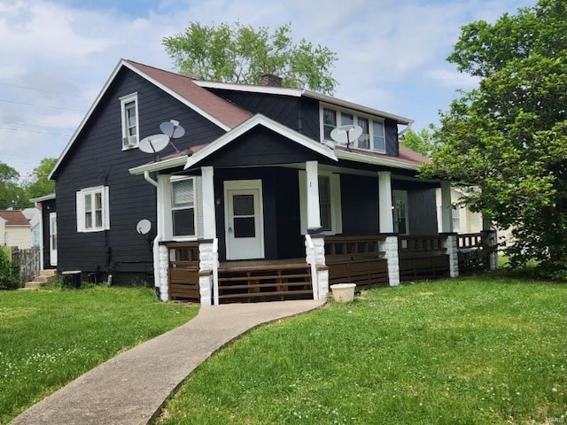 view of front of property with covered porch, a front lawn, and a chimney