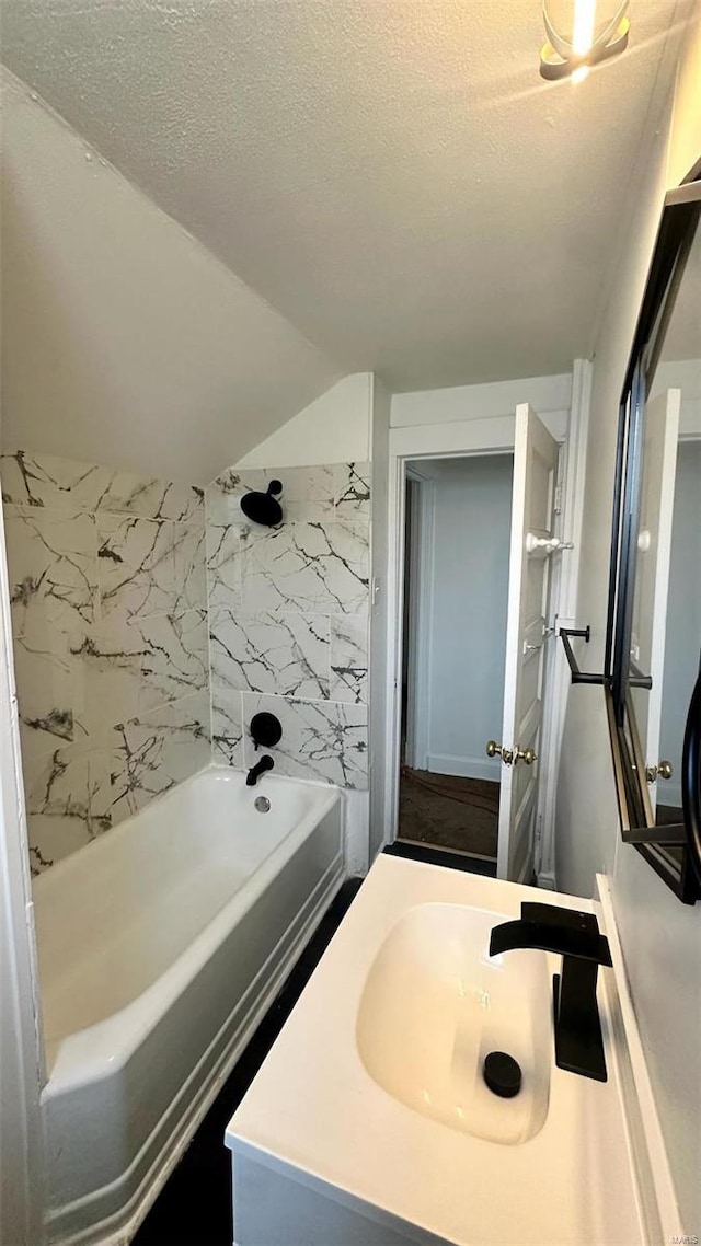 bathroom featuring tub / shower combination, vanity, a textured ceiling, and lofted ceiling