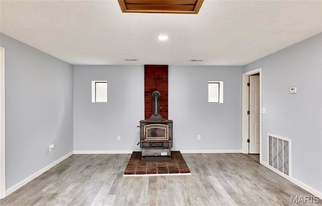 10994 Webster Rd, Caledonia, MO 63631 - unfurnished living room featuring a wood stove, healthy amount of natural light, a textured ceiling, and wood finished floors