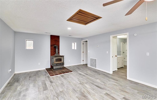 10994 Webster Rd, Caledonia, MO 63631 - unfurnished living room featuring wood finished floors, ceiling fan, a textured ceiling, and a wood stove