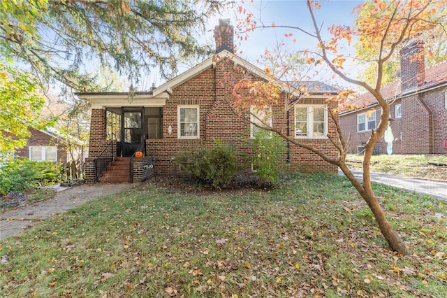 7510 Springdale Dr, Saint Louis, MO 63121 - view of front facade featuring a chimney, brick siding, a front yard, and a sunroom
