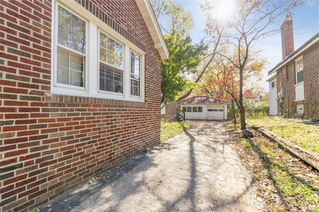 7510 Springdale Dr, Saint Louis, MO 63121 - view of side of home featuring an outdoor structure, brick siding, a detached garage, and driveway