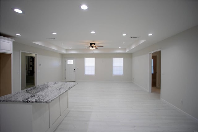 interior space with a ceiling fan, light wood-style flooring, a tray ceiling, and recessed lighting