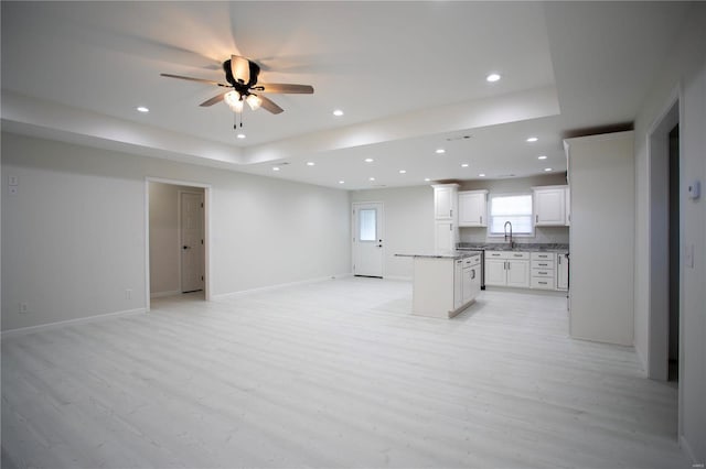 kitchen featuring open floor plan, a center island, a ceiling fan, light wood-type flooring, and white cabinetry