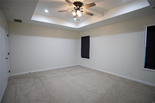 spare room featuring a raised ceiling, carpet floors, a ceiling fan, baseboards, and recessed lighting