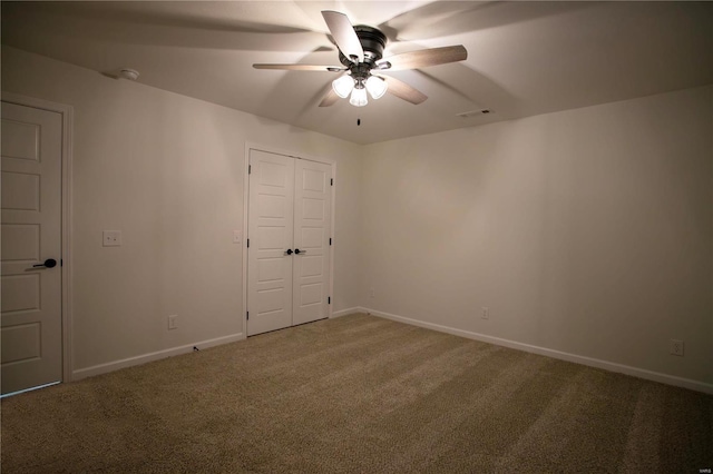 carpeted empty room with a ceiling fan and baseboards