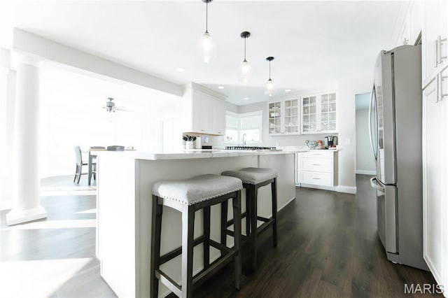 10605 Larson Ln, Rolla, MO 65401 - kitchen featuring freestanding refrigerator, decorative columns, glass insert cabinets, a breakfast bar, and recessed lighting