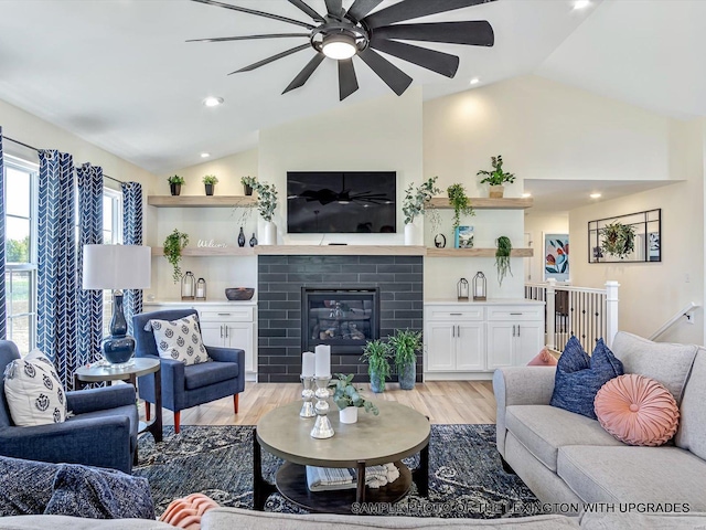 living room featuring vaulted ceiling, ceiling fan, light wood-type flooring, a fireplace, and recessed lighting
